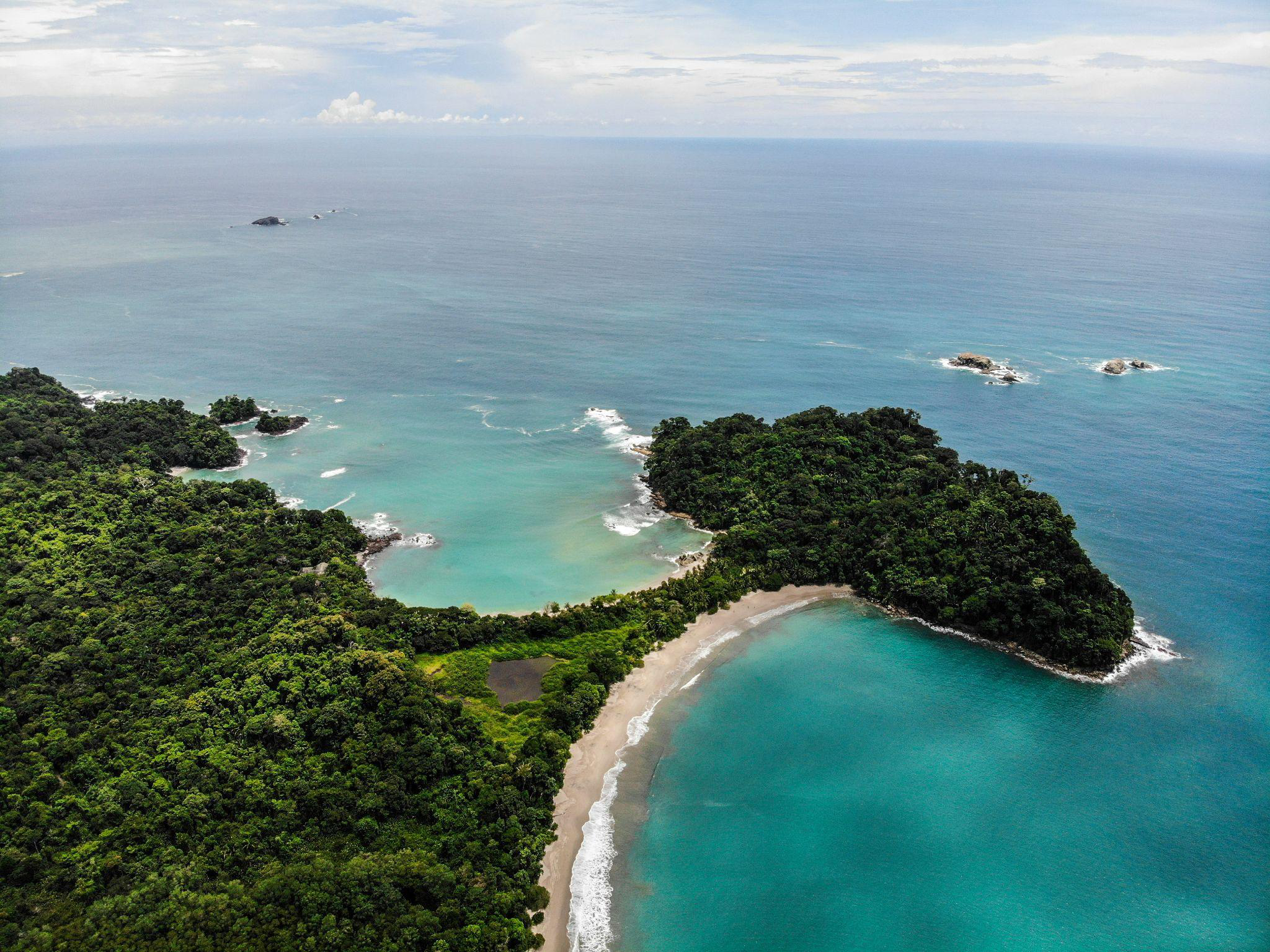 Aerial view of Costa Rica’s coastline with turquoise waters and green forested land.