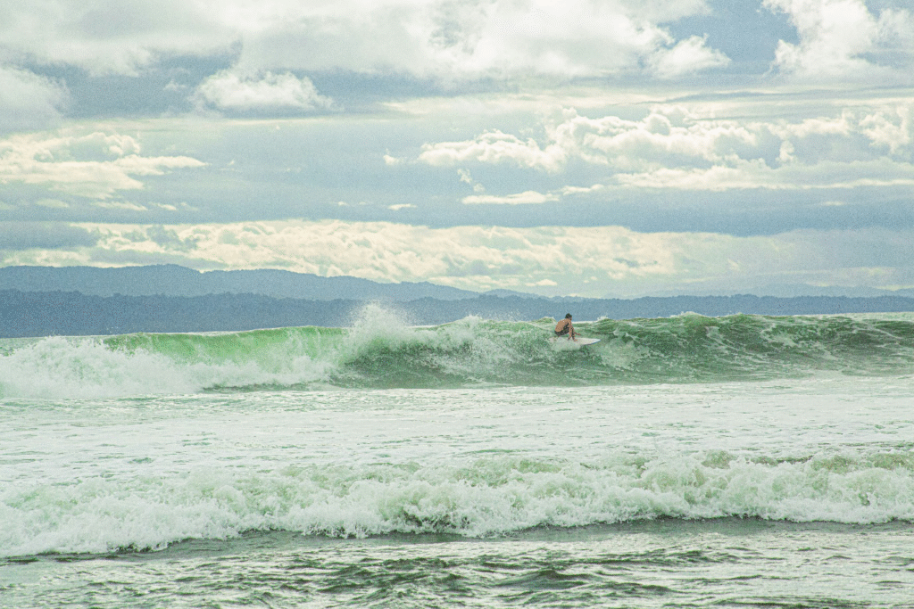 Surfer riding a wave on a cloudy day at a beach in Costa Rica