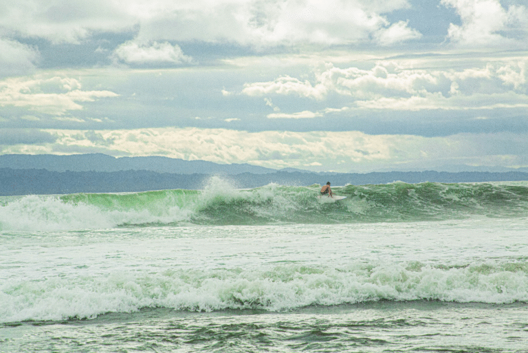 Surfer riding a wave on a cloudy day at a beach in Costa Rica